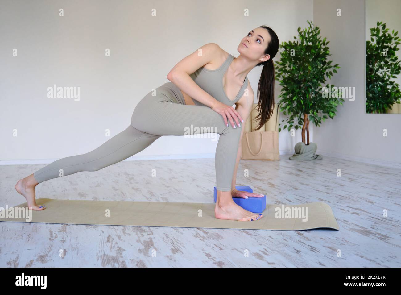 Junge schöne Frau praktiziert Yoga in einem hellen modernen Studio. Gesunder Lebensstil. Stockfoto