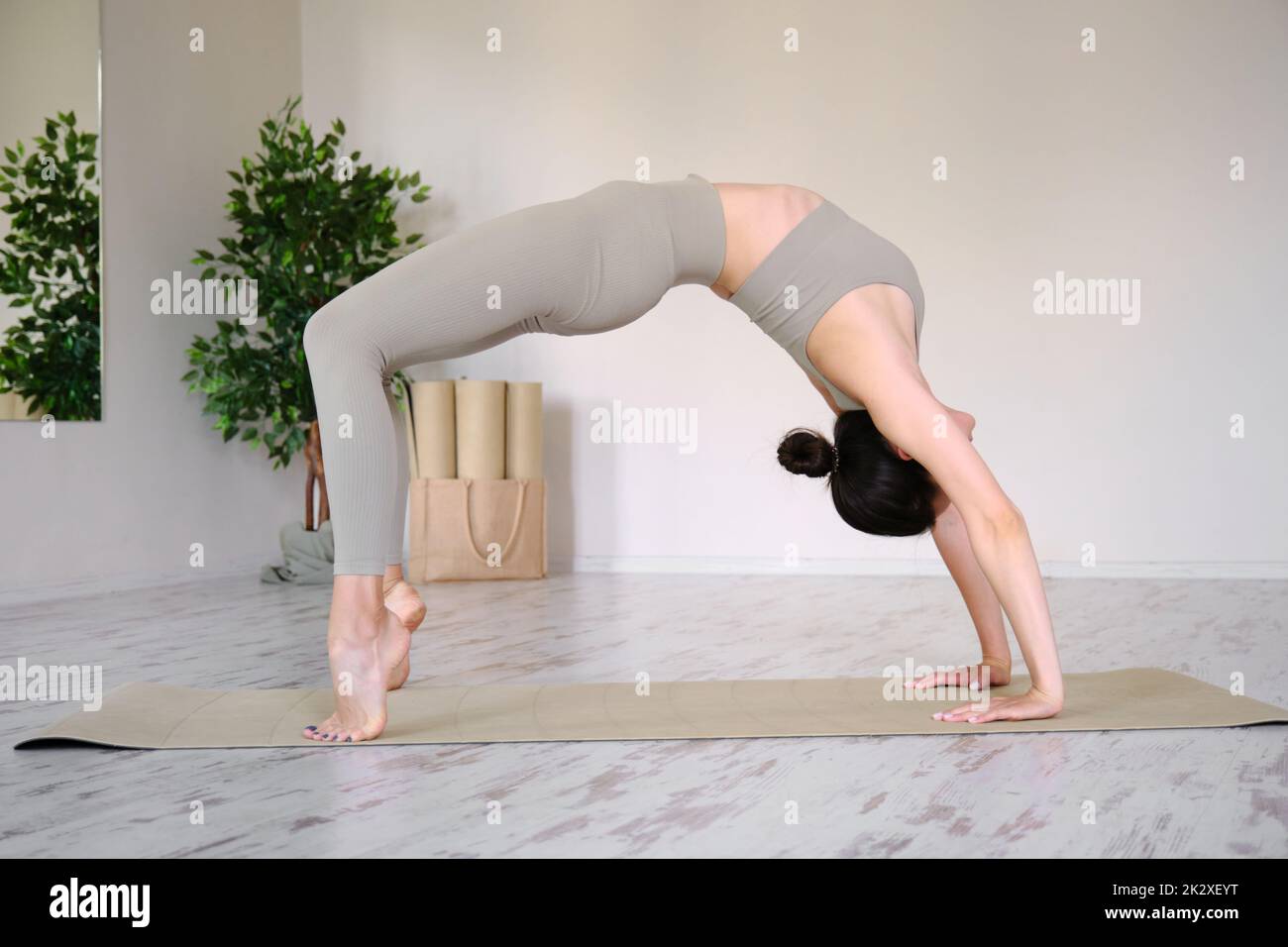 Eine junge schöne Frau praktiziert Yoga im Studio, steht in einer Bogenpose. Stockfoto