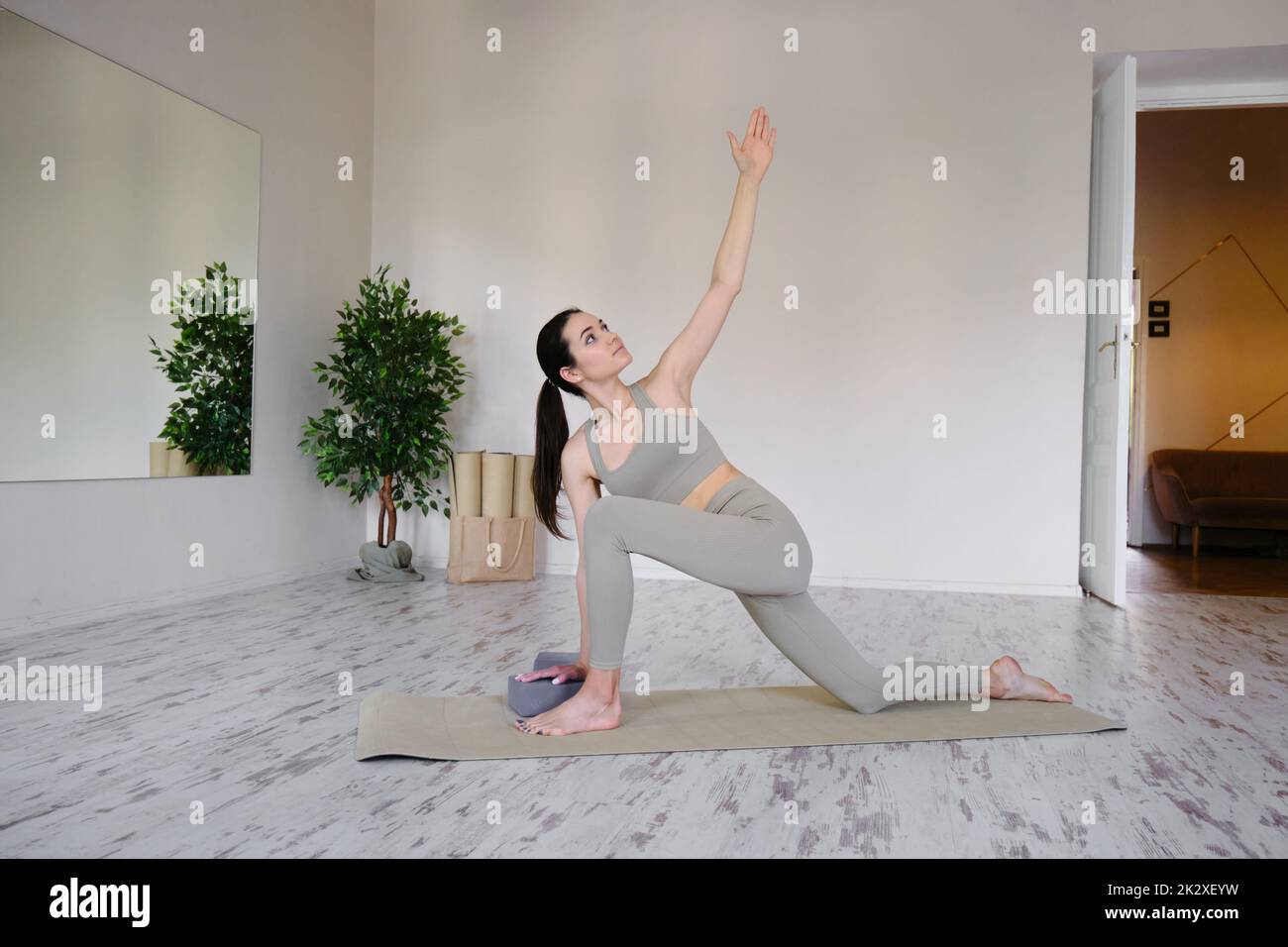 Ziemlich positive junge Brünette Frau macht Utthita parsvakonasana Übung, Yoga und Pilates Stockfoto