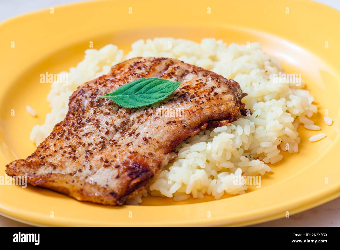 Weißer Fisch auf Kreuzkümmel, serviert mit Reis Stockfoto