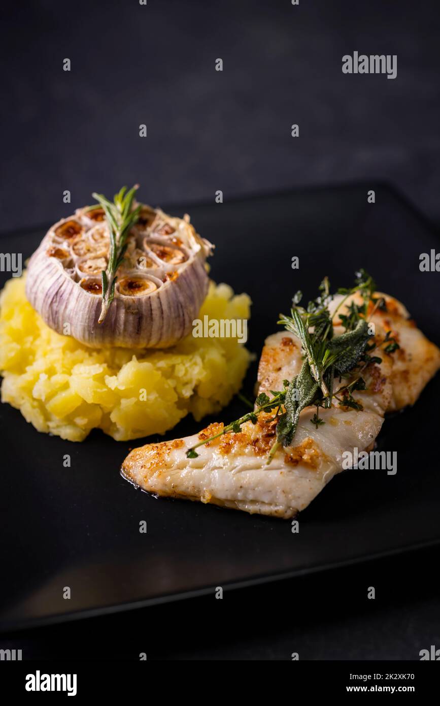 Kabeljaufilet mit Couscous und geröstetem Knoblauch Stockfoto