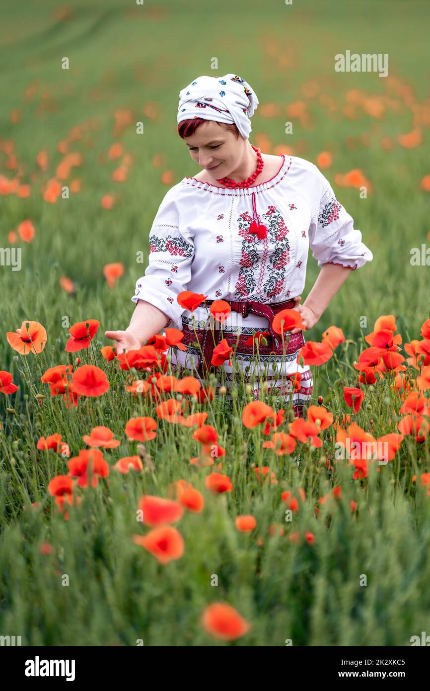 Frau in ukrainischer Nationaltracht auf einem blühenden Mohnfeld Stockfoto