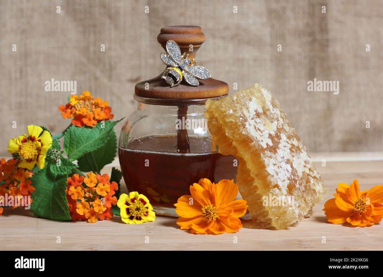 Frischer Honig mit Honigwaben und Blumen in rustikaler Küche Stockfoto