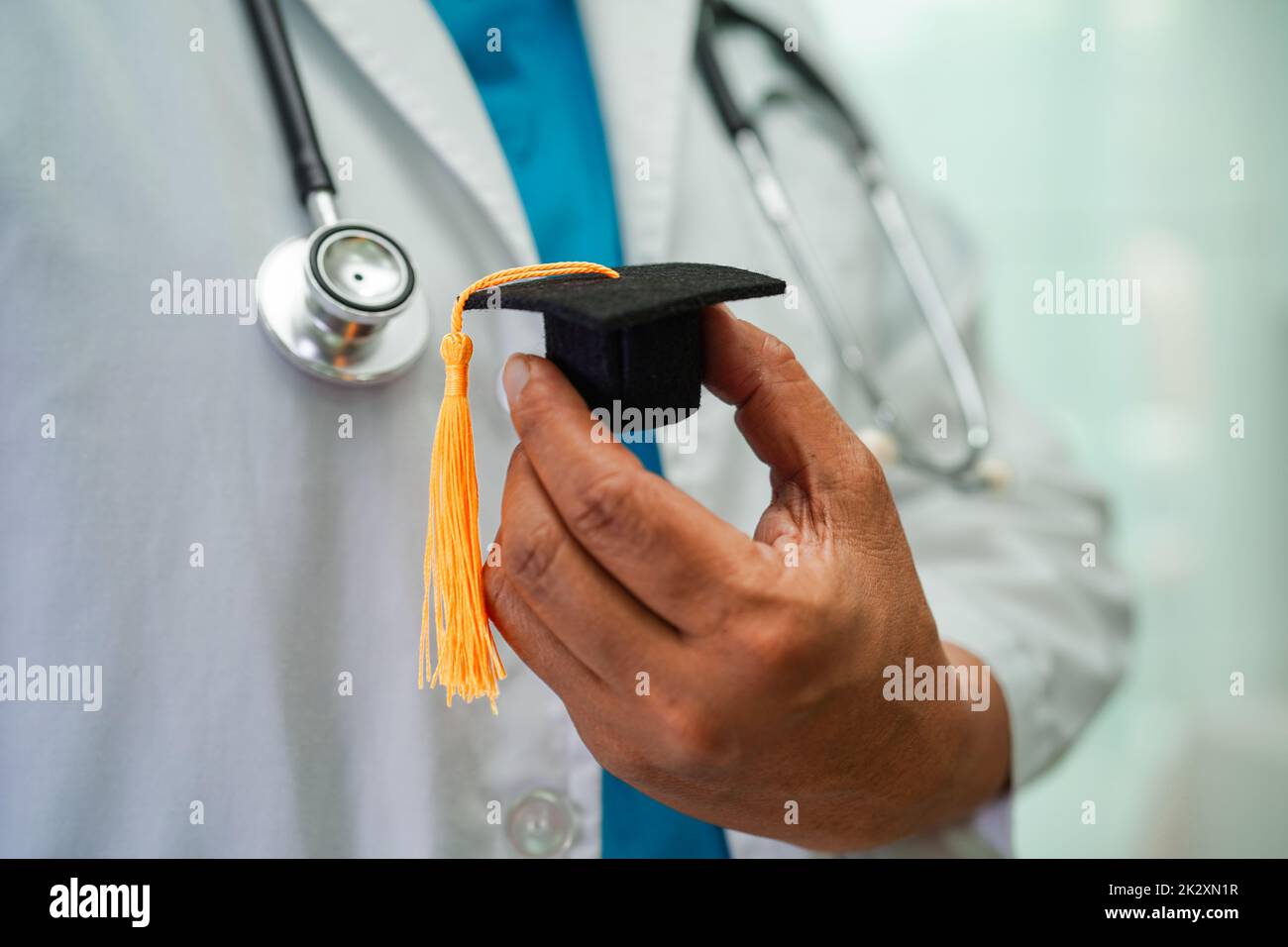 Asiatische Frau Arzt hält Abschlusshut im Krankenhaus, Medizinische Ausbildung Konzept. Stockfoto