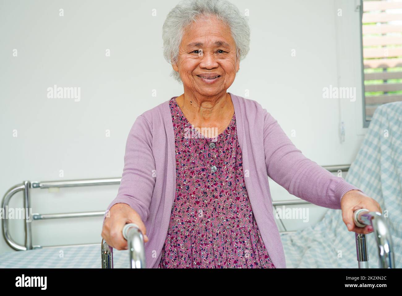 Ältere asiatische ältere Frau, Patientin sitzt und lächelt im Krankenhaus glücklich im Bett. Stockfoto