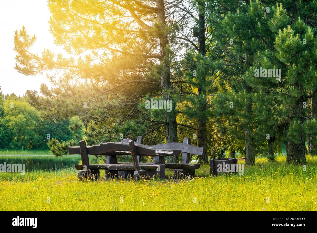 Rustikaler Holztisch und Bänke am Ufer eines ruhigen Flusses oder Sees Stockfoto