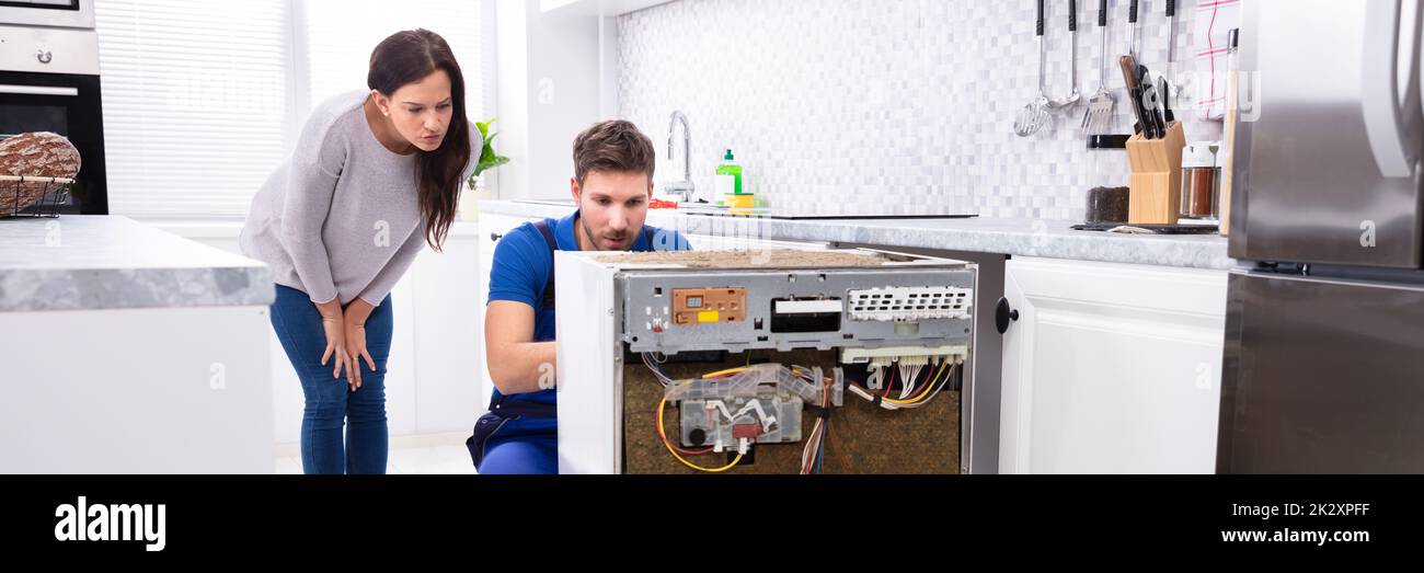 Der Servicemitarbeiter Repariert Die Spülmaschine In Der Küche Stockfoto