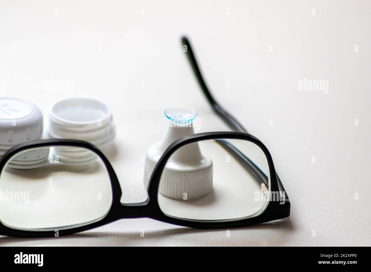 Blaue Kontaktlinse durch die schwarze Brille zeigt verschiedene Brillen, um durch Optometrie Weitsicht und Kurzsichtigkeit zu korrigieren, oder Augenarzt gegen Myopie mit Augenkorrektur für perfektes Sehen Stockfoto