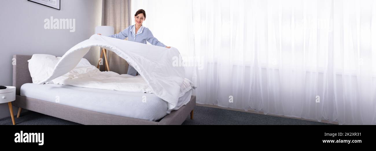 Haushälterin, die die Bettlaken auf dem Bett Stockfoto