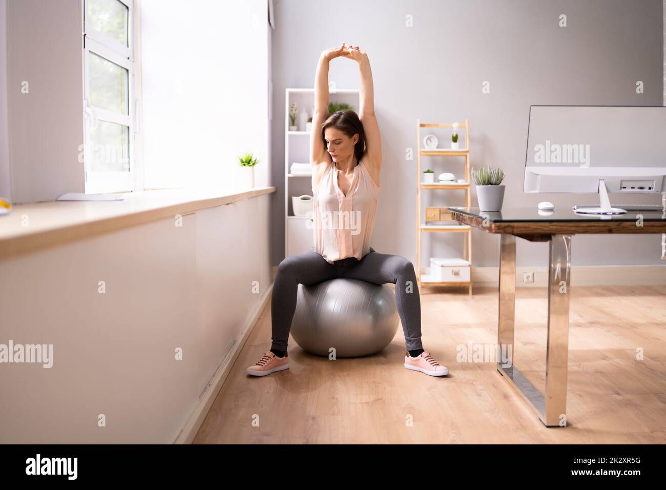 Glückliche Geschäftsfrau, Die Sich Auf Dem Fitnessball Im Büro Entspannen Kann Stockfoto