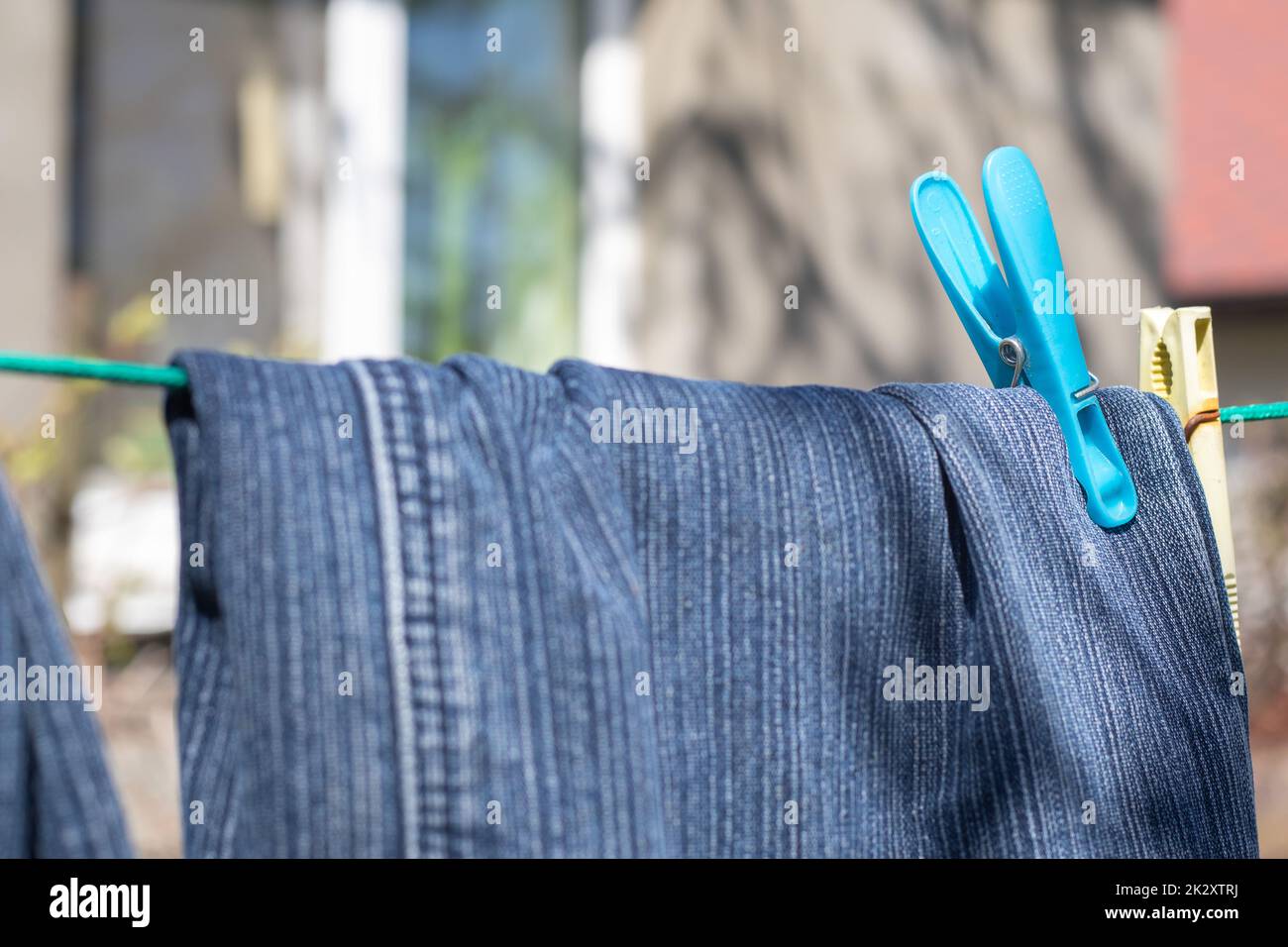 Jeans hängen an einem sonnigen Sommertag an der Wäscheleine. Blick auf frisch gewaschene Jeans. Stockfoto