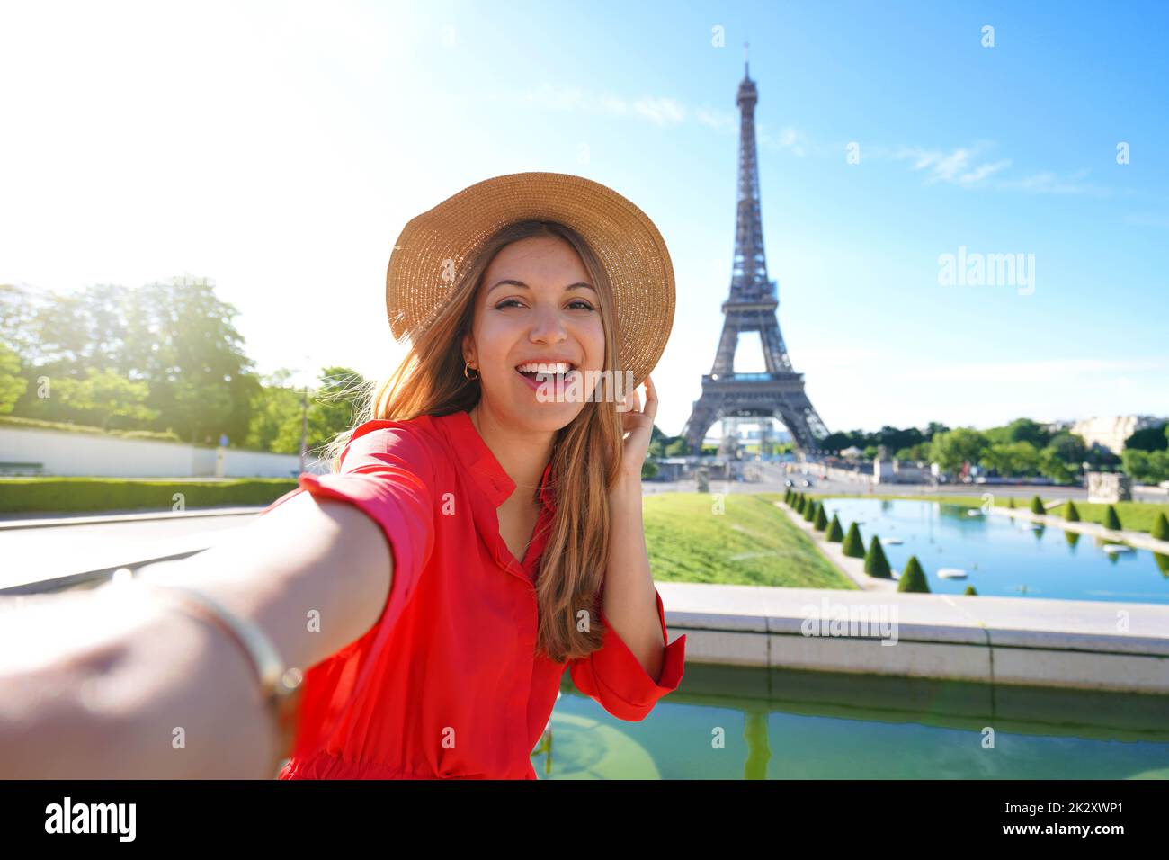 Mode-Tourist Frau mit rotem Kleid und Hut macht Selfie-Foto mit Eiffelturm auf dem Hintergrund in Paris, Frankreich. Konzeptreise. Stockfoto