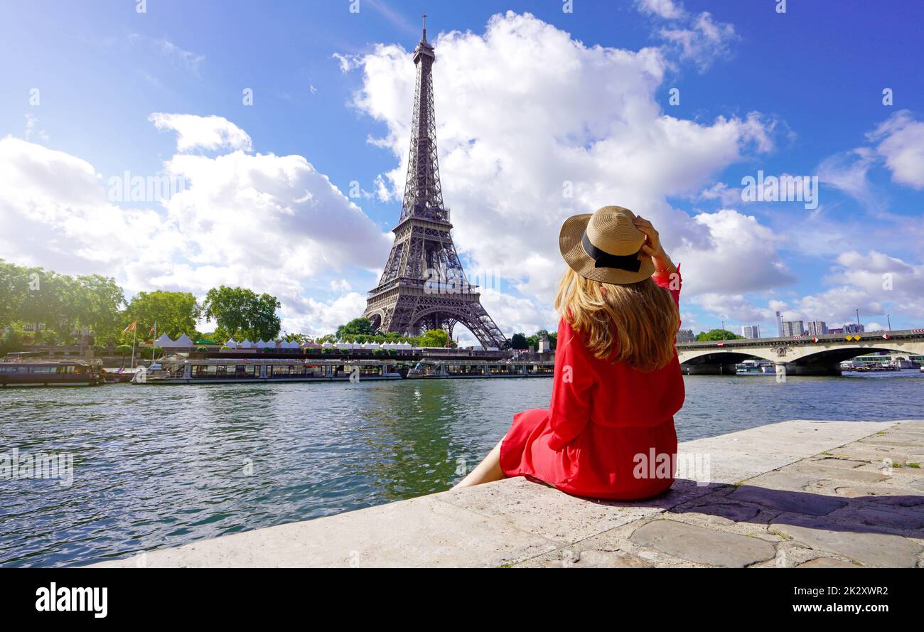 Junge Reisende Frau in rotem Kleid und Hut am Kai der seine mit Blick auf den Eiffelturm, das berühmte Wahrzeichen und Reiseziel in Paris. Stockfoto