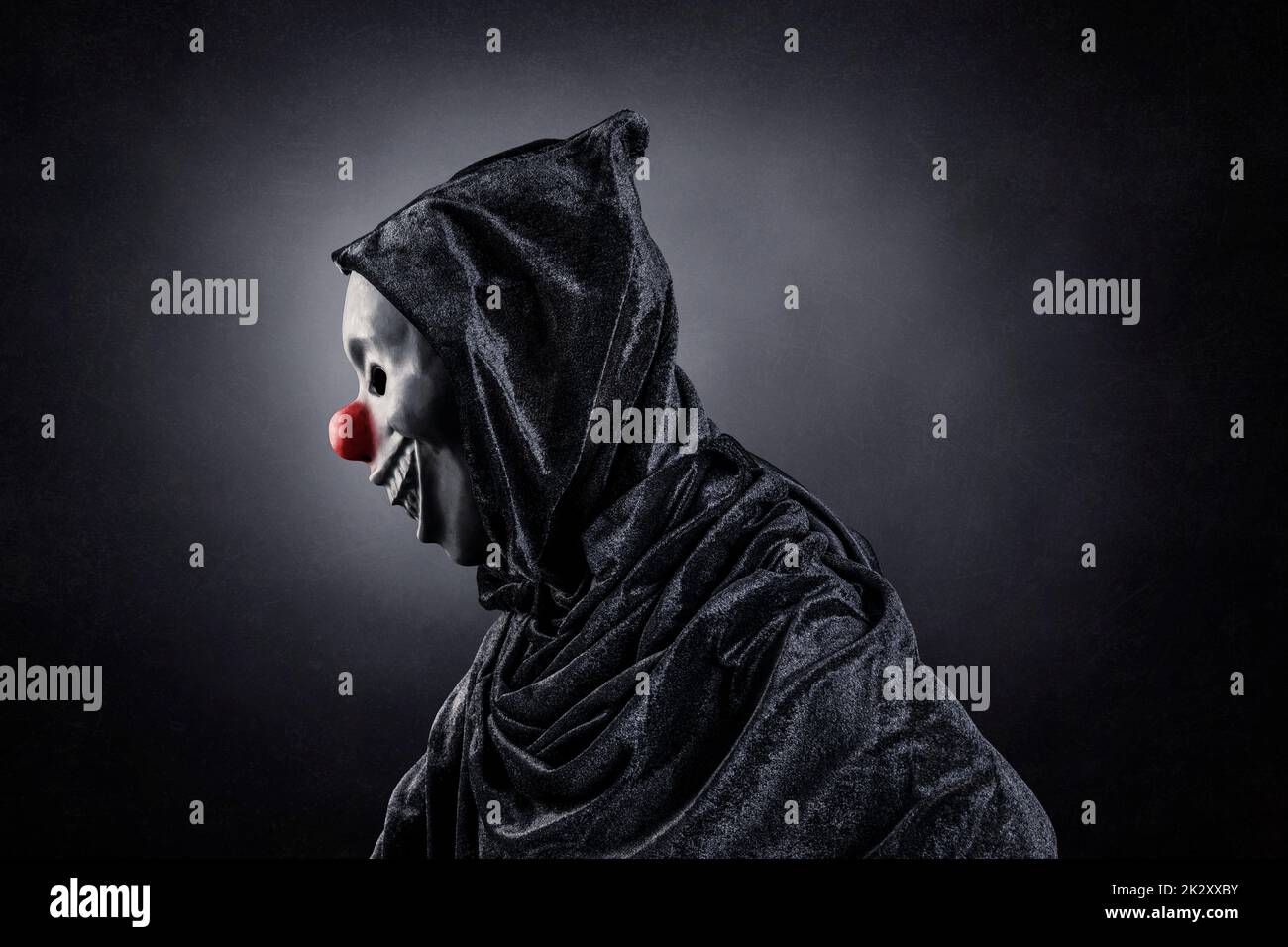 Scary Clown zeigt seine Zähne über dunklen nebligen Hintergrund Stockfoto