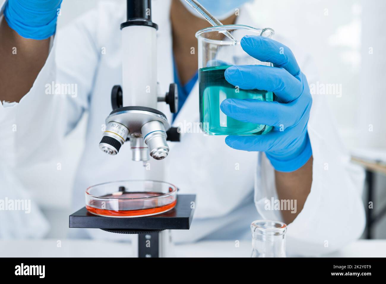 Asian Wissenschaftler Biochemiker oder Mikrobiologe arbeiten Forschung mit einem Mikroskop im Labor. Zum Schutz vor Ausbruch Coronavirus Covid19, Bakterien und Keimen. Stockfoto
