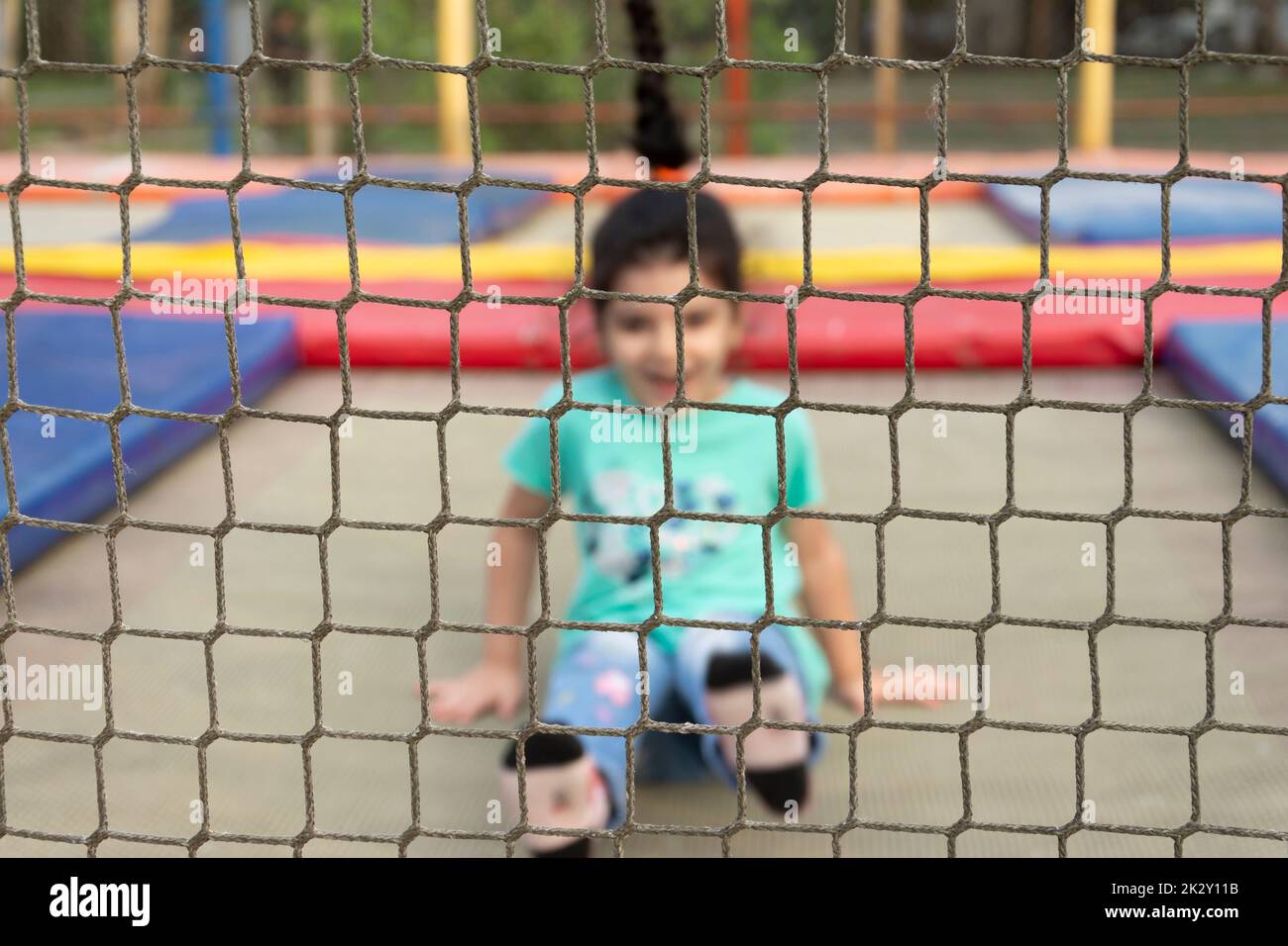 Kleines Mädchen, das Spaß auf Trampolin im Park im Außenbereich hat Stockfoto