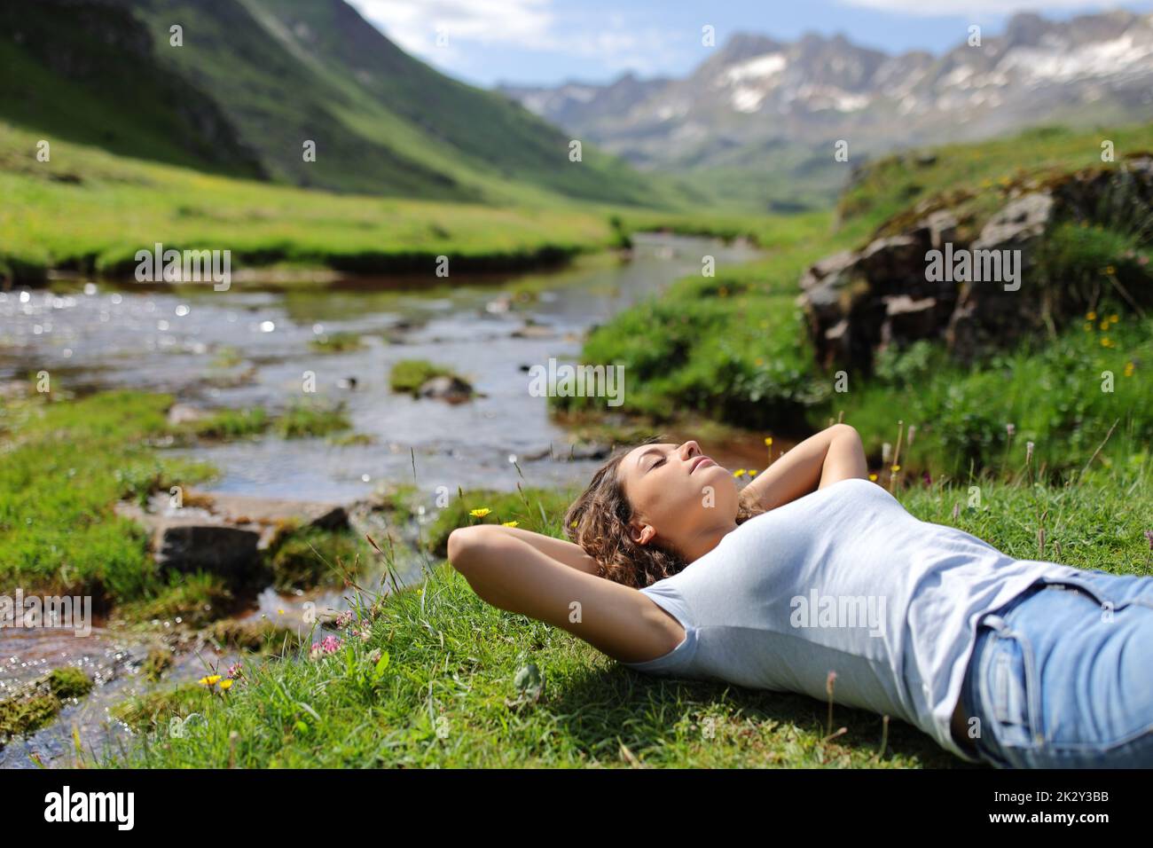 Eine Frau, die am Flussufer in den Bergen ruht Stockfoto