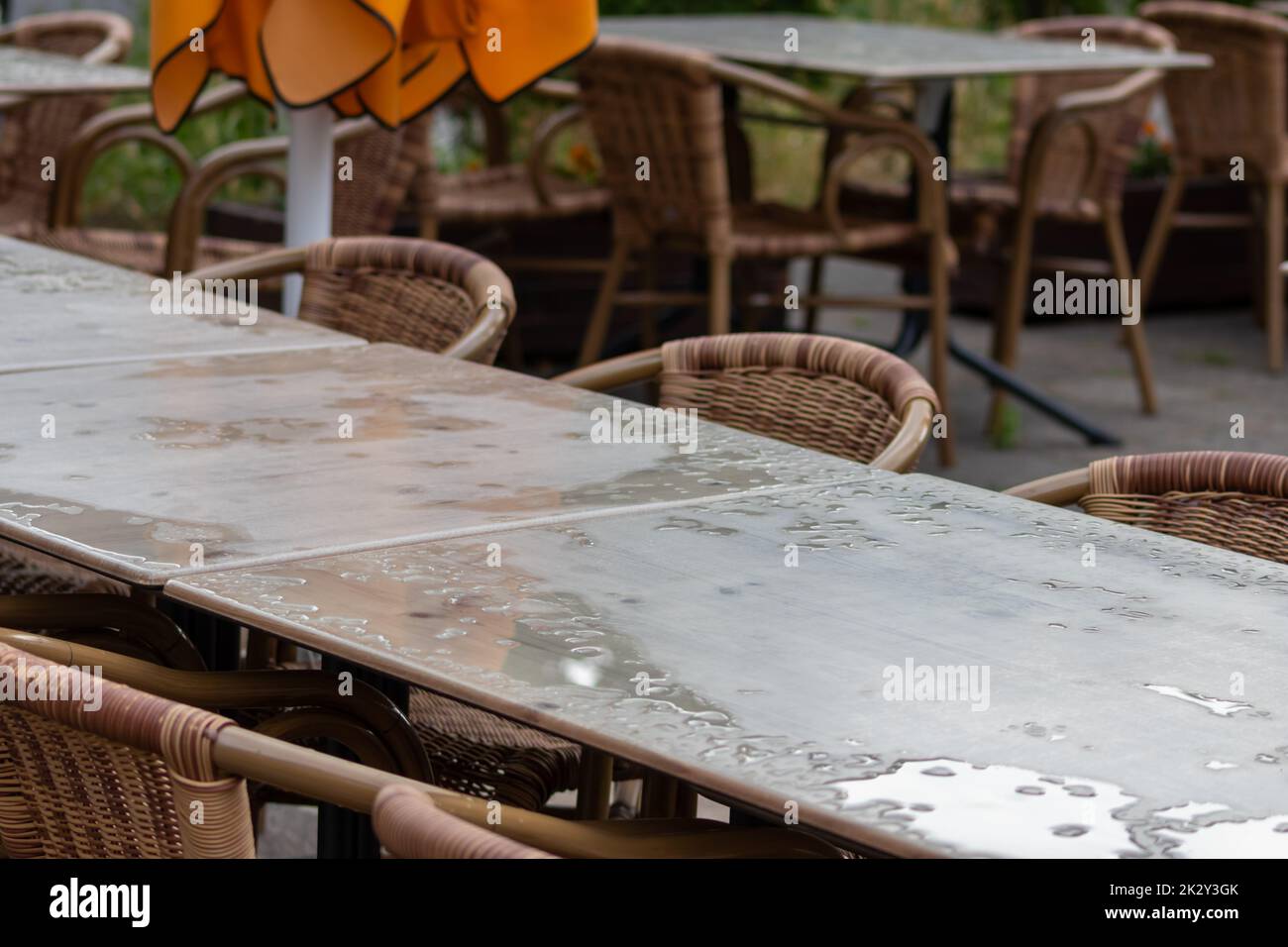 Leerer Tisch und leere Stühle im Sommerrestaurant oder Biergarten im Sommer an regnerischen Tagen mit Regentropfen und keine Gäste, kein Einkommen auf Bürgersteigen im regnerischen Sommer in pandemischen Lockdown-Restaurants Stockfoto