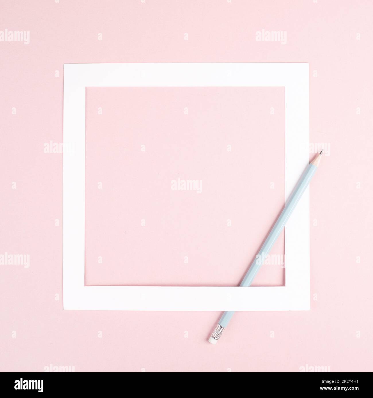Bleistift auf rosafarbenem Papierhintergrund, weißer Rahmen mit Platz für Text, Minimalismus, kreatives und geschäftliches Konzept, pastellfarben Stockfoto