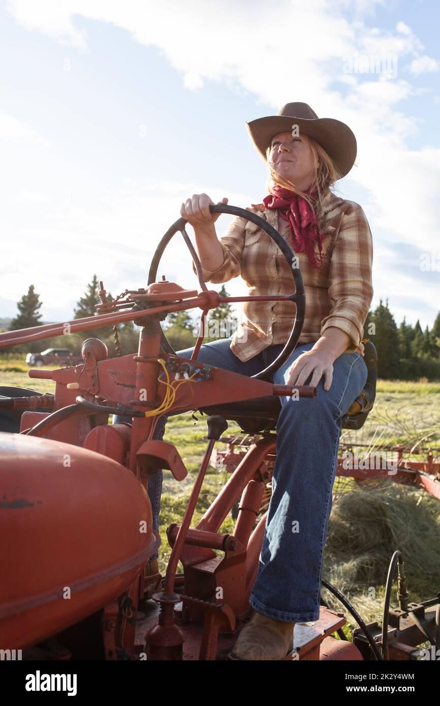 Bäuerin im Cowboy hat Traktor in sonnigen ländlichen Feld fahren Stockfoto