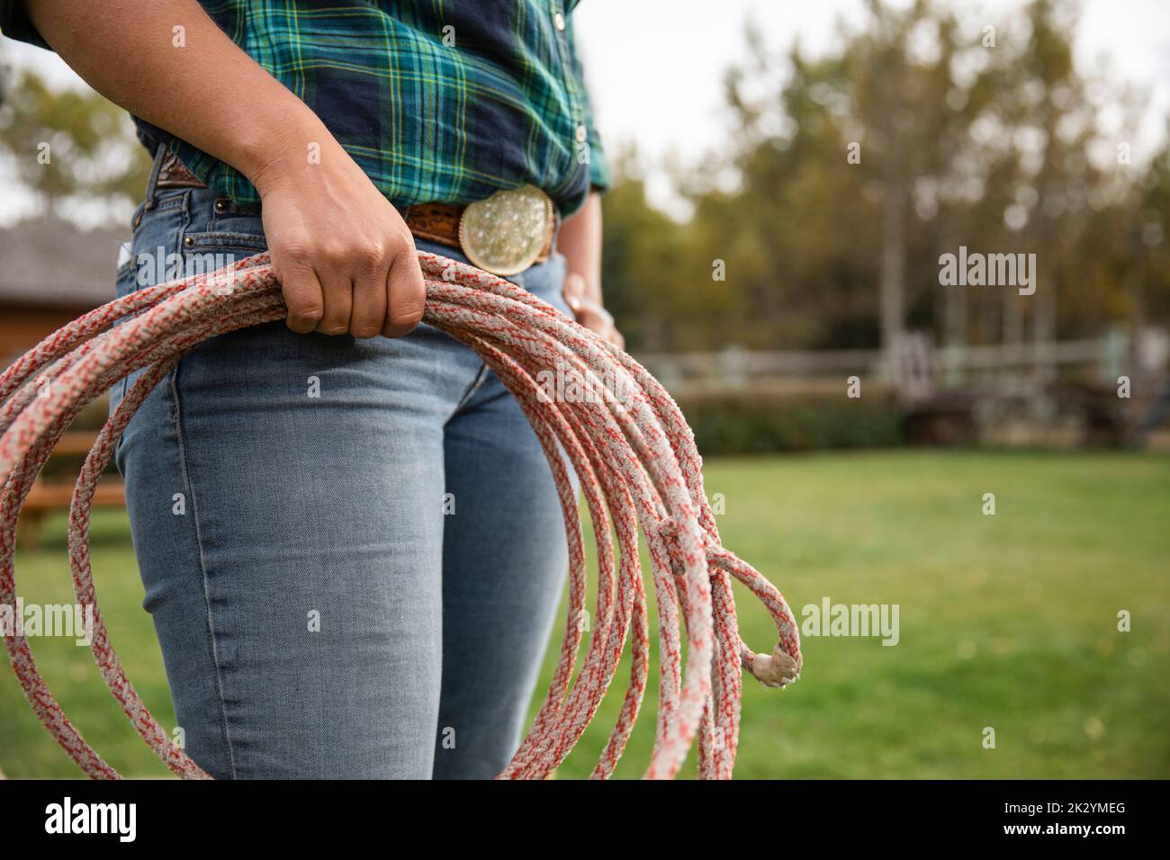 Nahaufnahme der weiblichen Rancherin mit Gürtelschnalle, die Lassoseil auf der Ranch hält Stockfoto