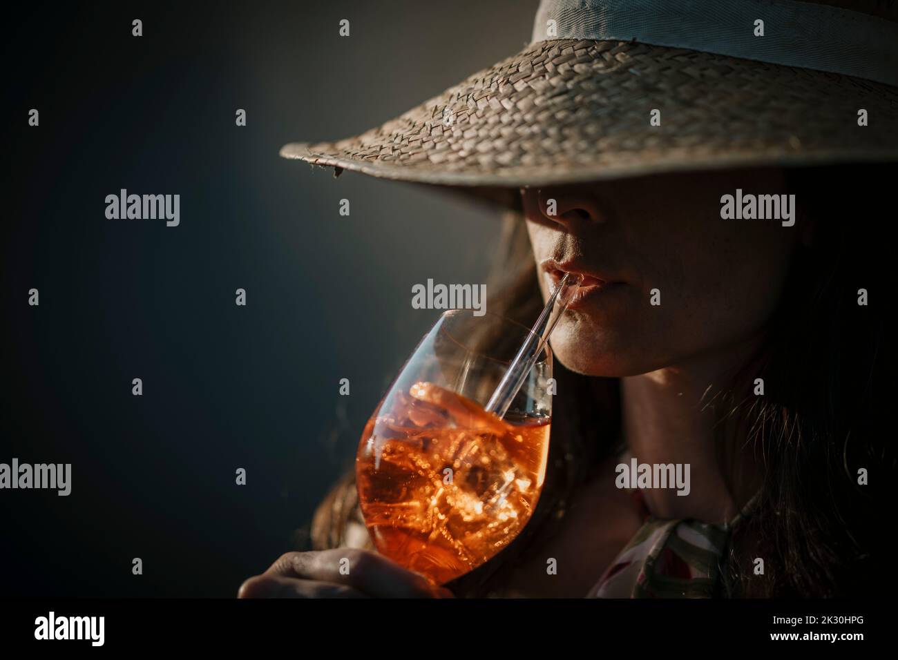 Frau mit Hut, die mit Stroh getrunken hat Stockfoto