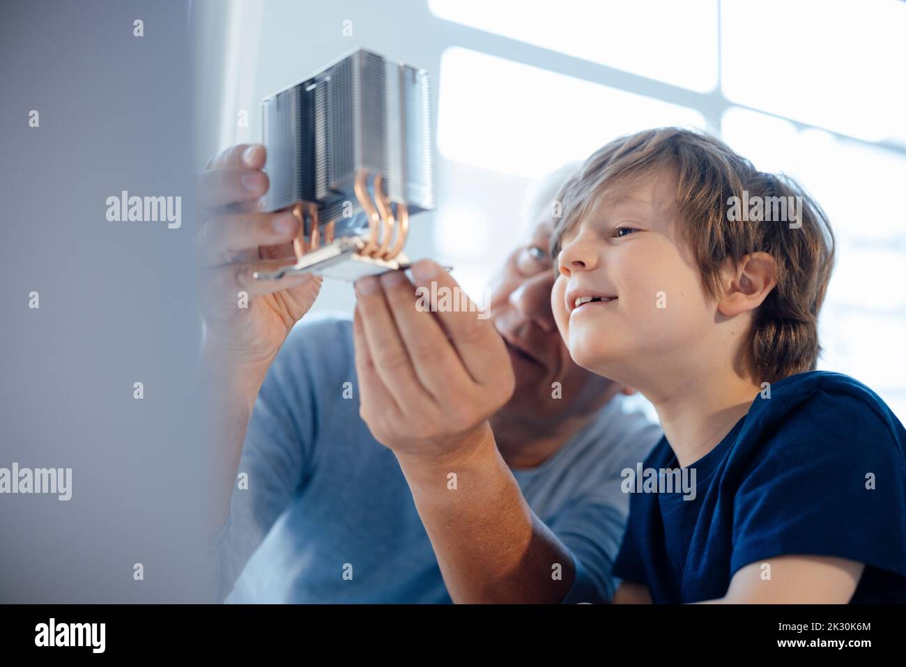 Großvater untersucht Modellobjekt von Enkel zu Hause Stockfoto