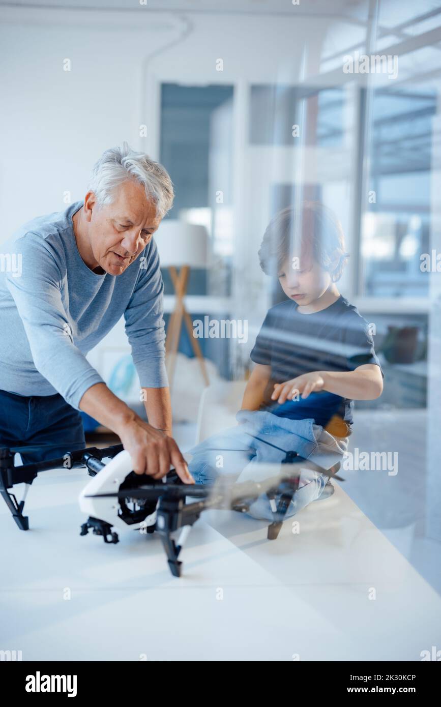 Älterer Mann untersucht Drohne von Enkel zu Hause Stockfoto