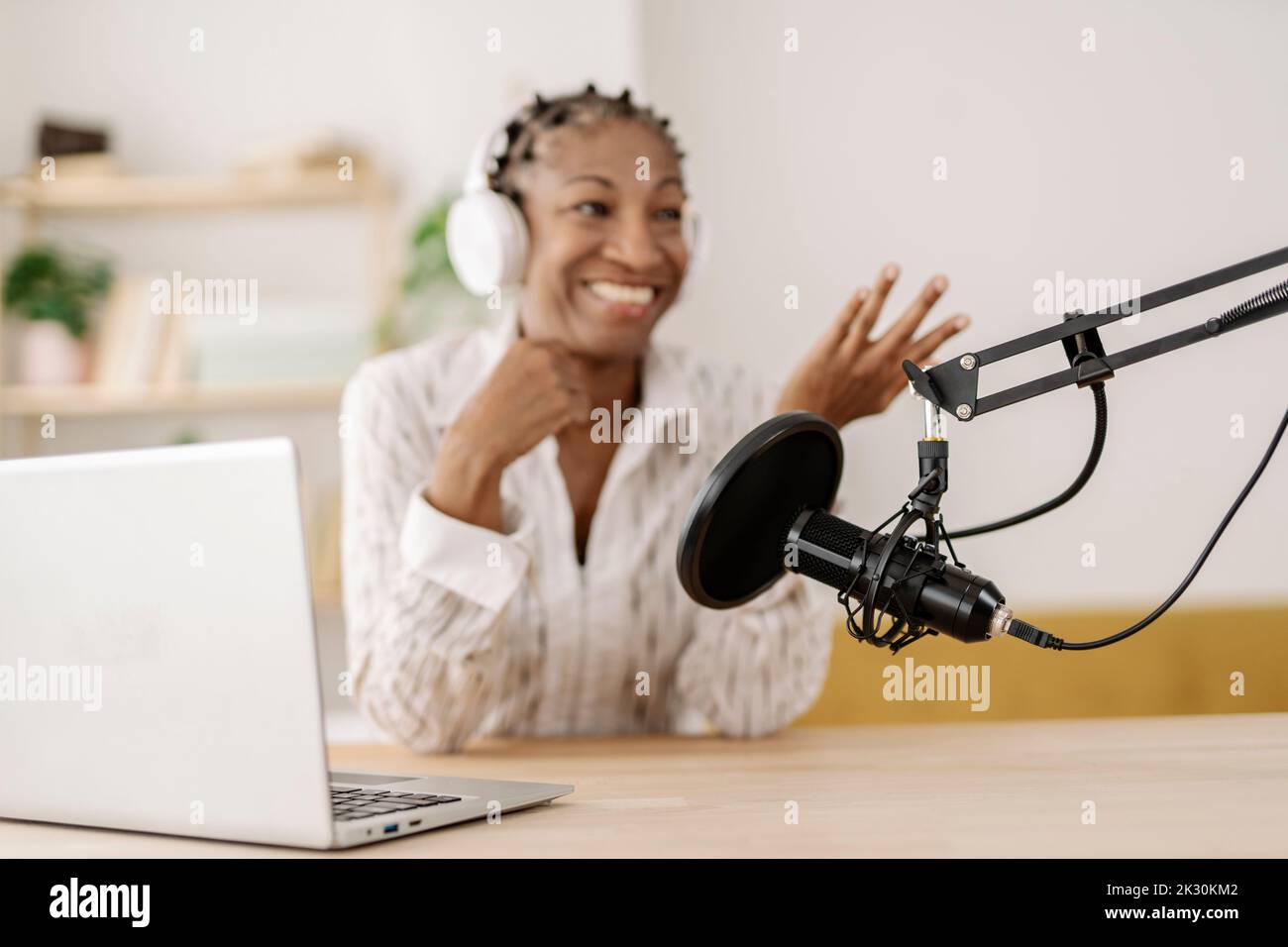 Lächelnder Freiberufler, der Podcast über das Mikrofon im Heimbüro aufnimmt Stockfoto