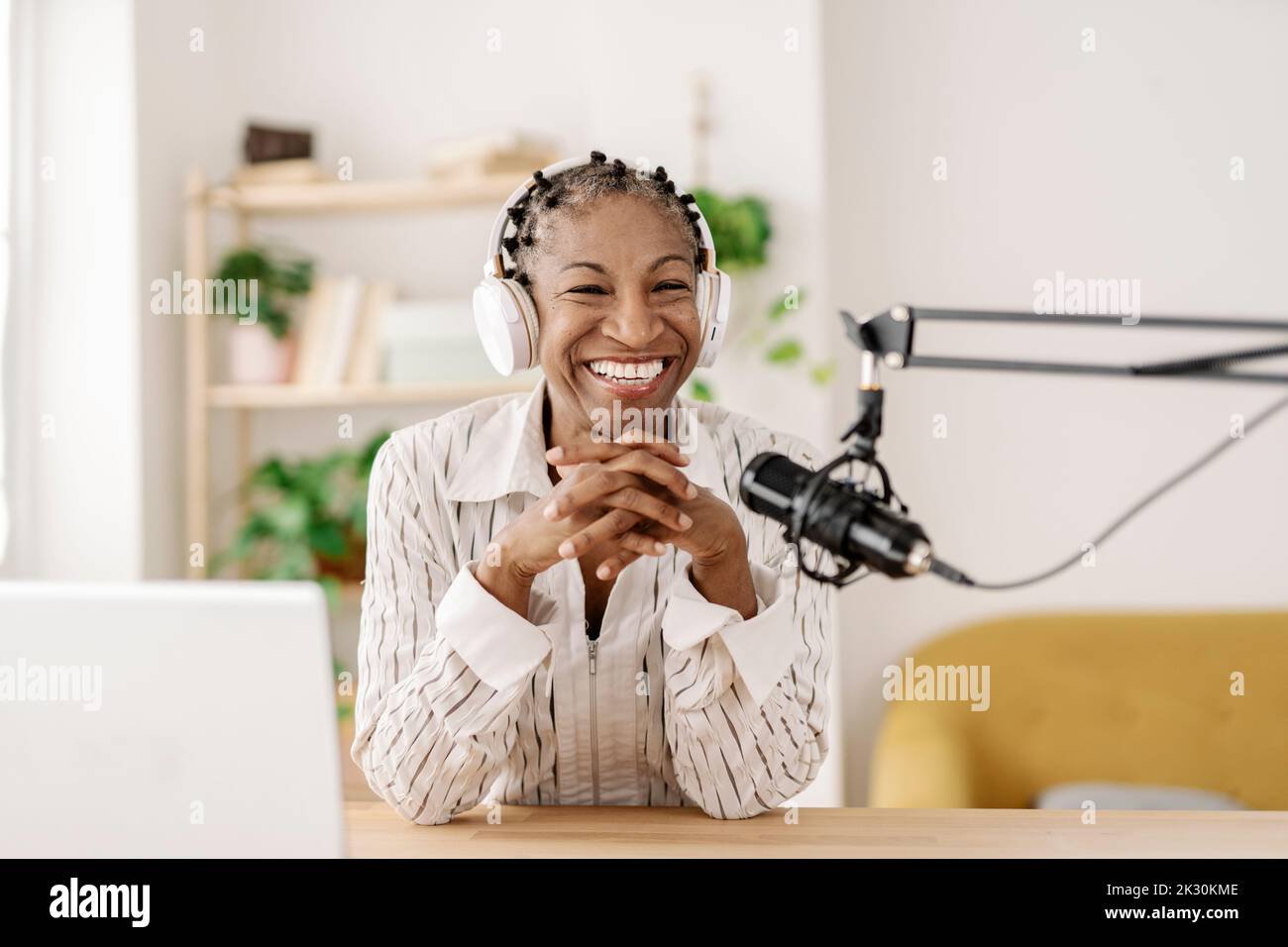 Fröhlicher Freiberufler, der Podcast über das Mikrofon im Heimbüro aufnimmt Stockfoto