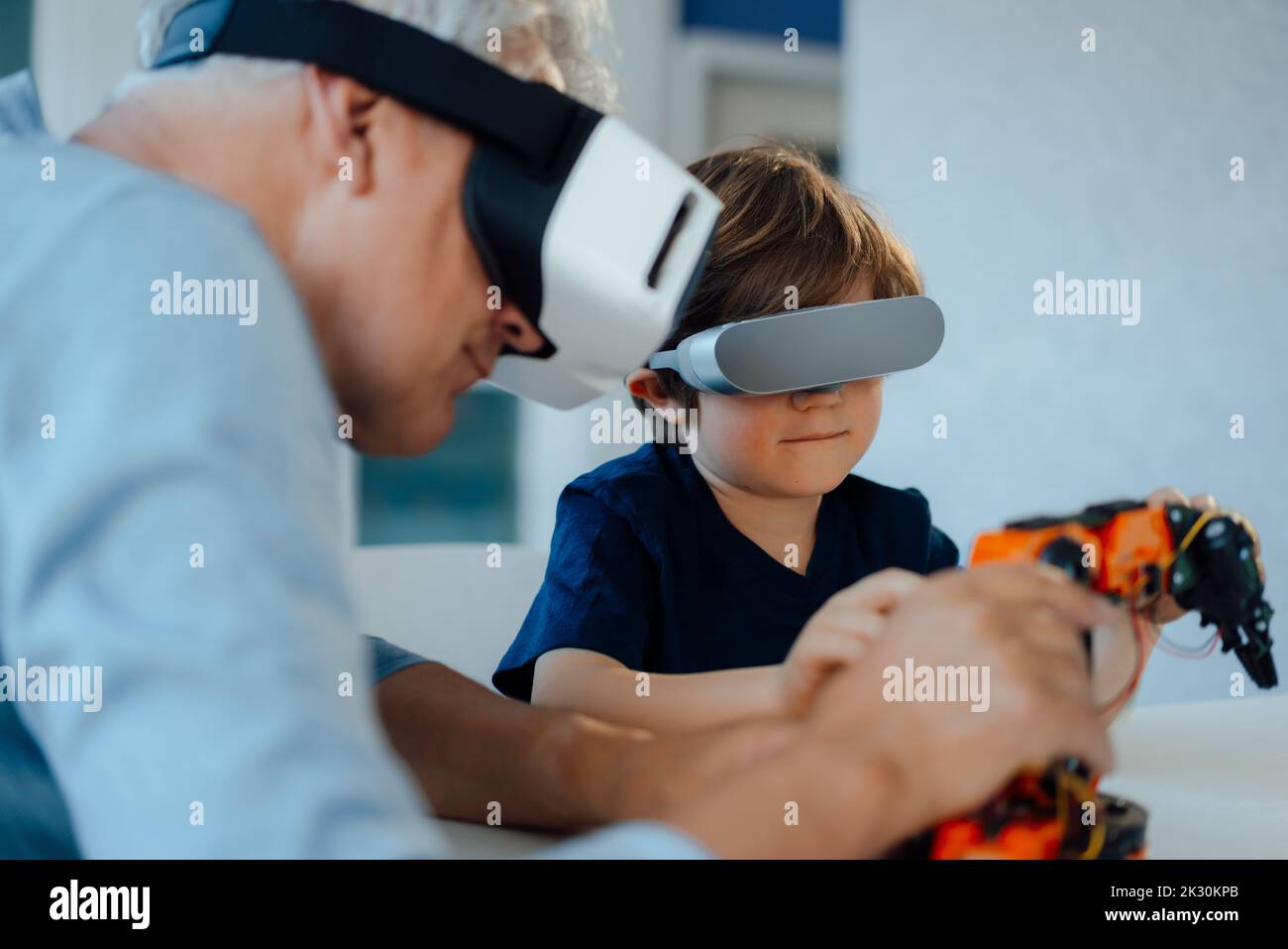 Großvater und Enkel mit VR-Brille beobachten Roboter-Modell zu Hause Stockfoto
