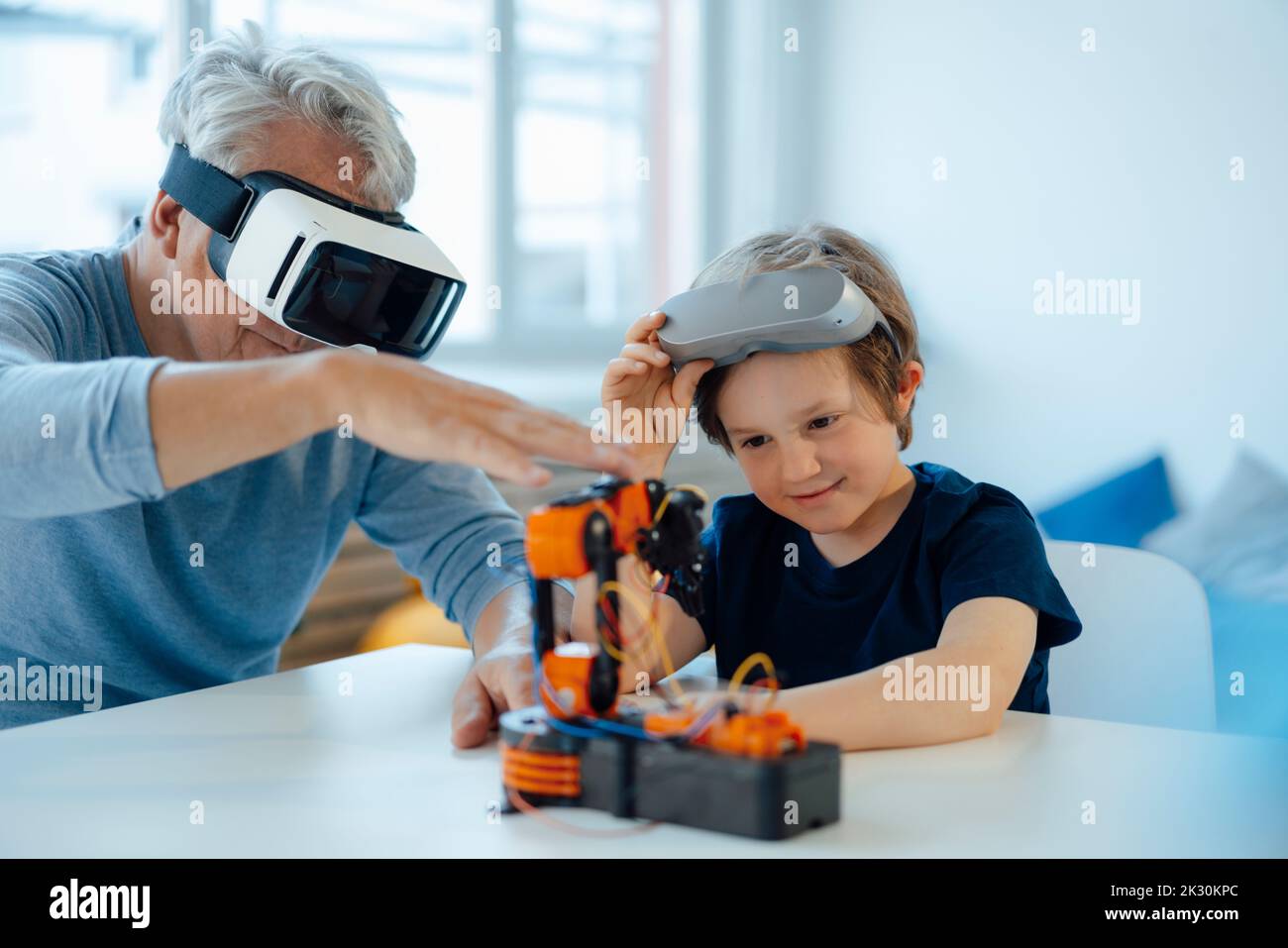 Junge untersucht Robot-Modell von Großvater mit VR-Brille zu Hause Stockfoto
