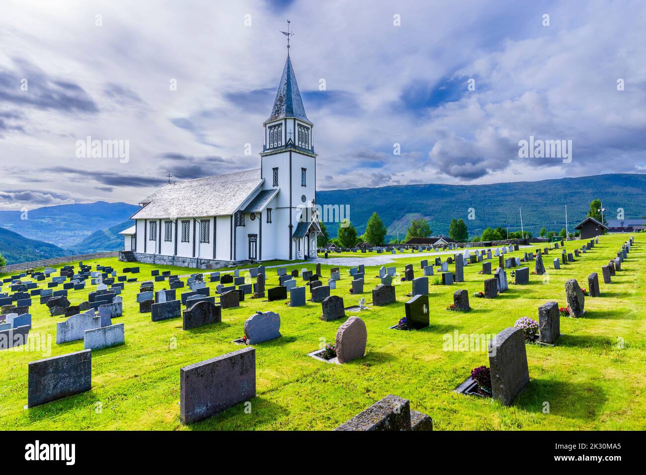 Norwegen, Viken, Gol, Grabsteine mit einer ländlichen Kirche im Hintergrund Stockfoto