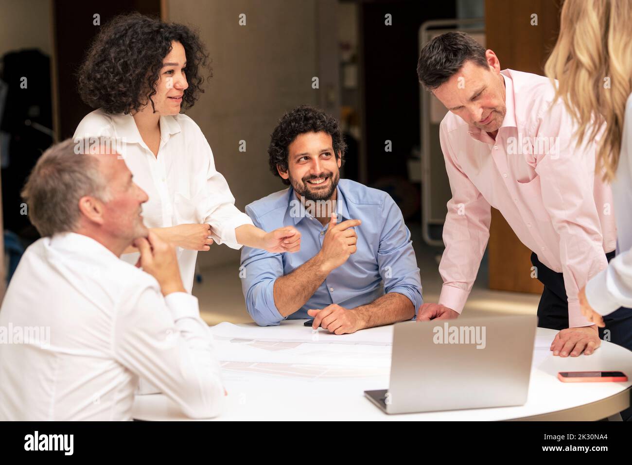 Lächelnder Geschäftsmann diskutiert über Dokument mit Kollegen im Korridor Stockfoto