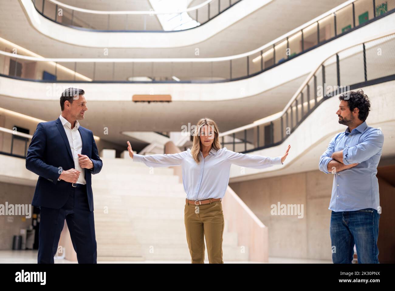 Geschäftsfrau hält Kollegen davon ab, sich in der Lobby zu streiten Stockfoto Geschäftsfrau hält Kollegen davon ab, sich in der Lobby zu streiten Stockfoto
