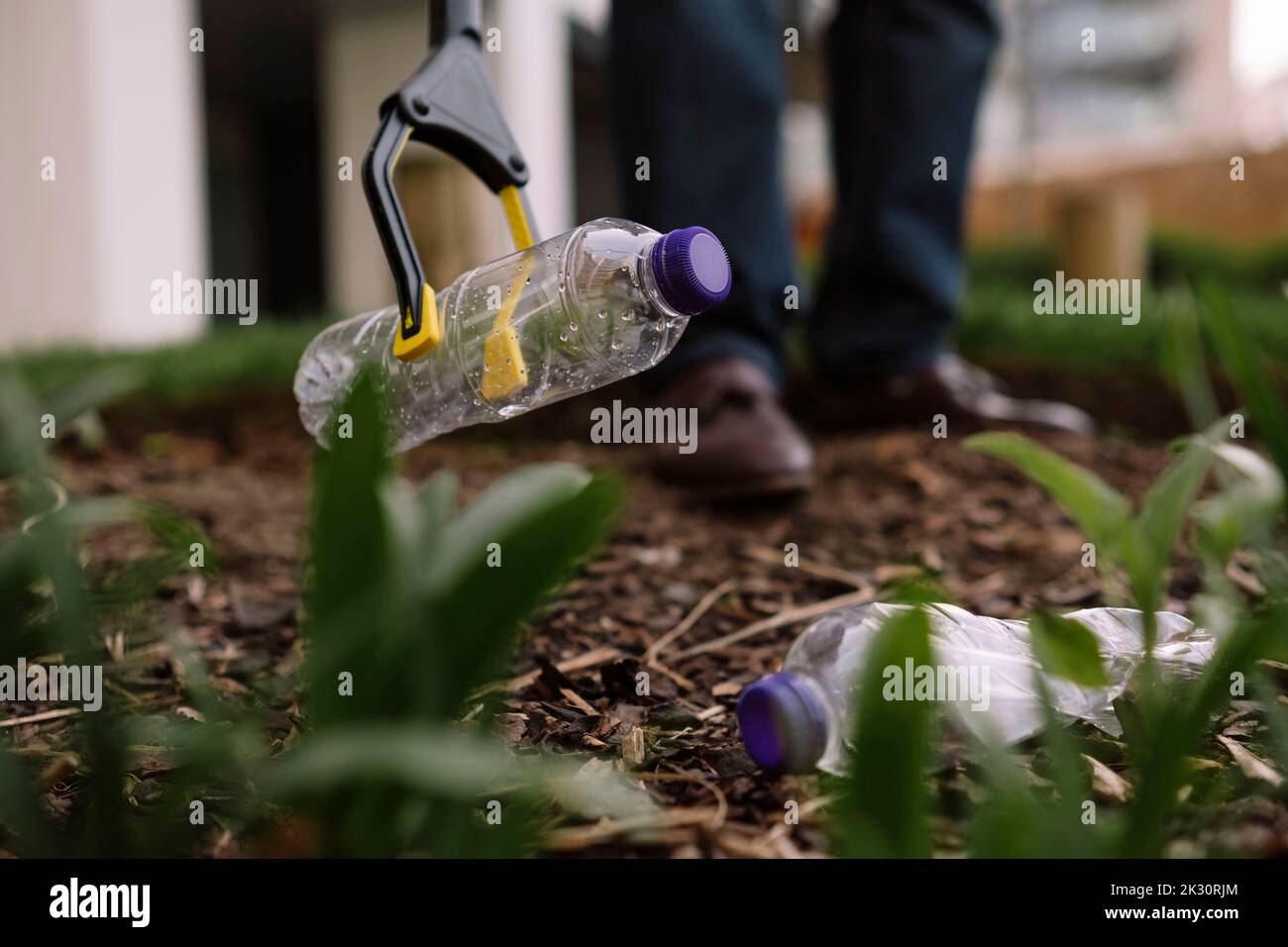 Reifer Mann, der leere Plastikflaschen mit Abfallsammler aus dem Park abholt Stockfoto