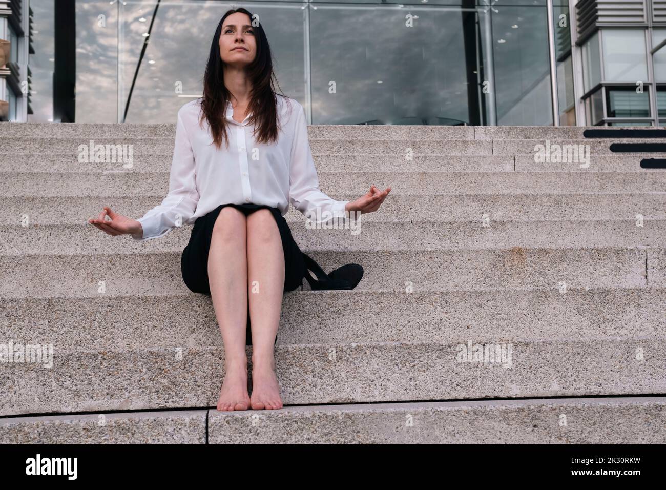 Nachdenkliche Geschäftsfrau, die Meditation auf Stufen macht Stockfoto