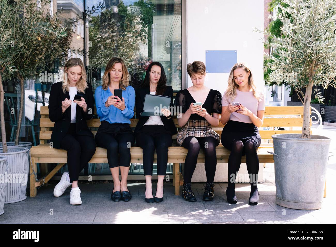 Geschäftsleute, die Smartphones und Tablet-PCs auf der Bank verwenden Stockfoto