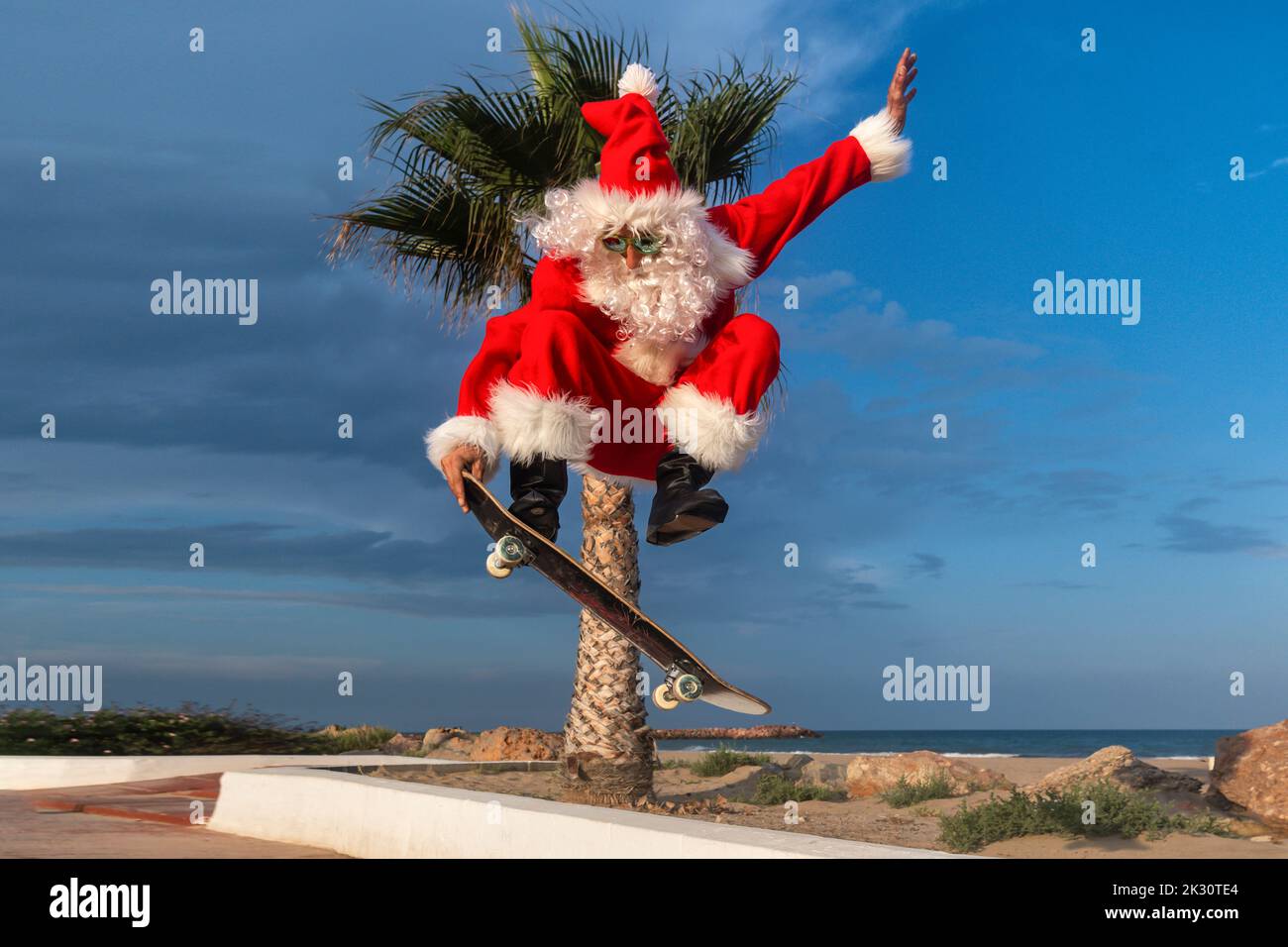 Reifer Mann trägt Santa Claus Kostüm Skateboarding auf Fußpfad Stockfoto