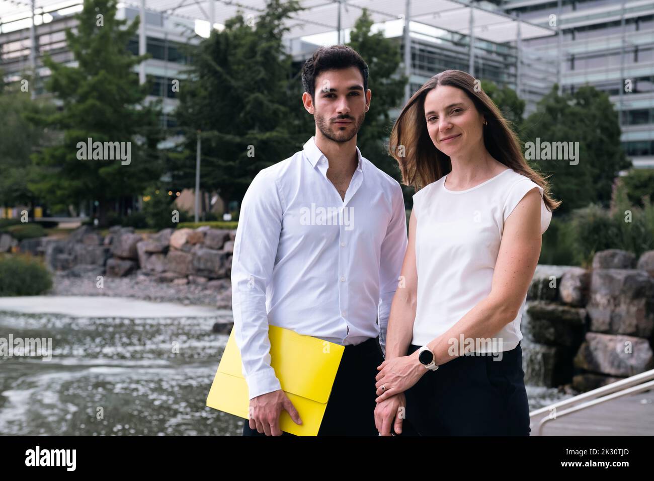Glückliche Geschäftskollegen stehen vor dem Teich im Büropark Stockfoto