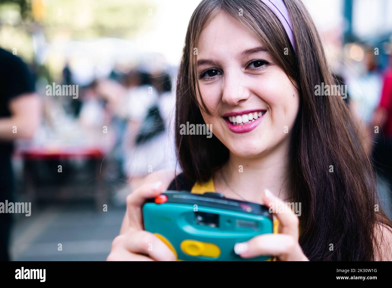 Glückliche Frau mit langen Haaren, die die Kamera hält Stockfoto Glückliche Frau mit langen Haaren, die die Kamera hält Stockfoto