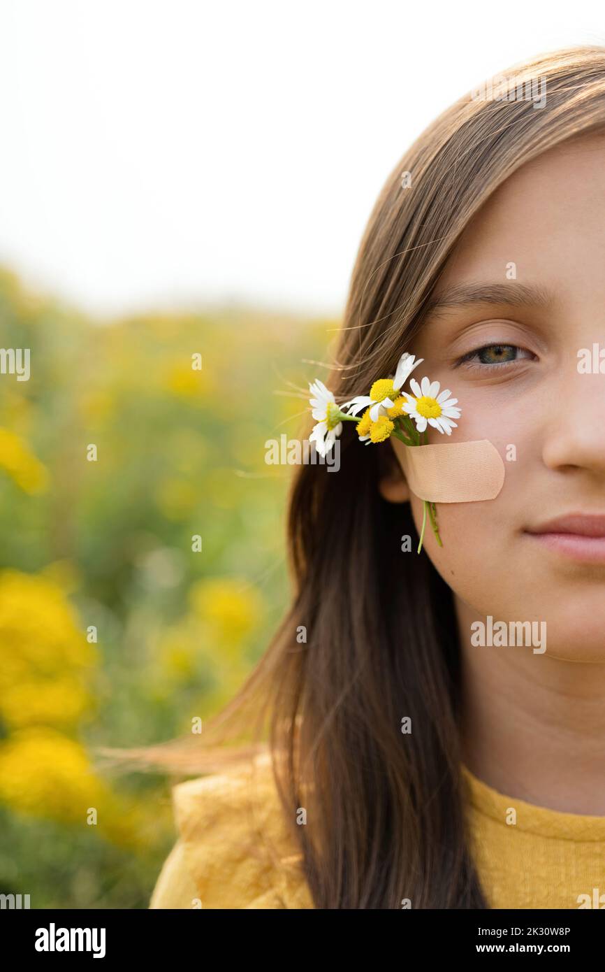 Mädchen mit Blumen auf der Wange durch klebende Verband befestigt Stockfoto