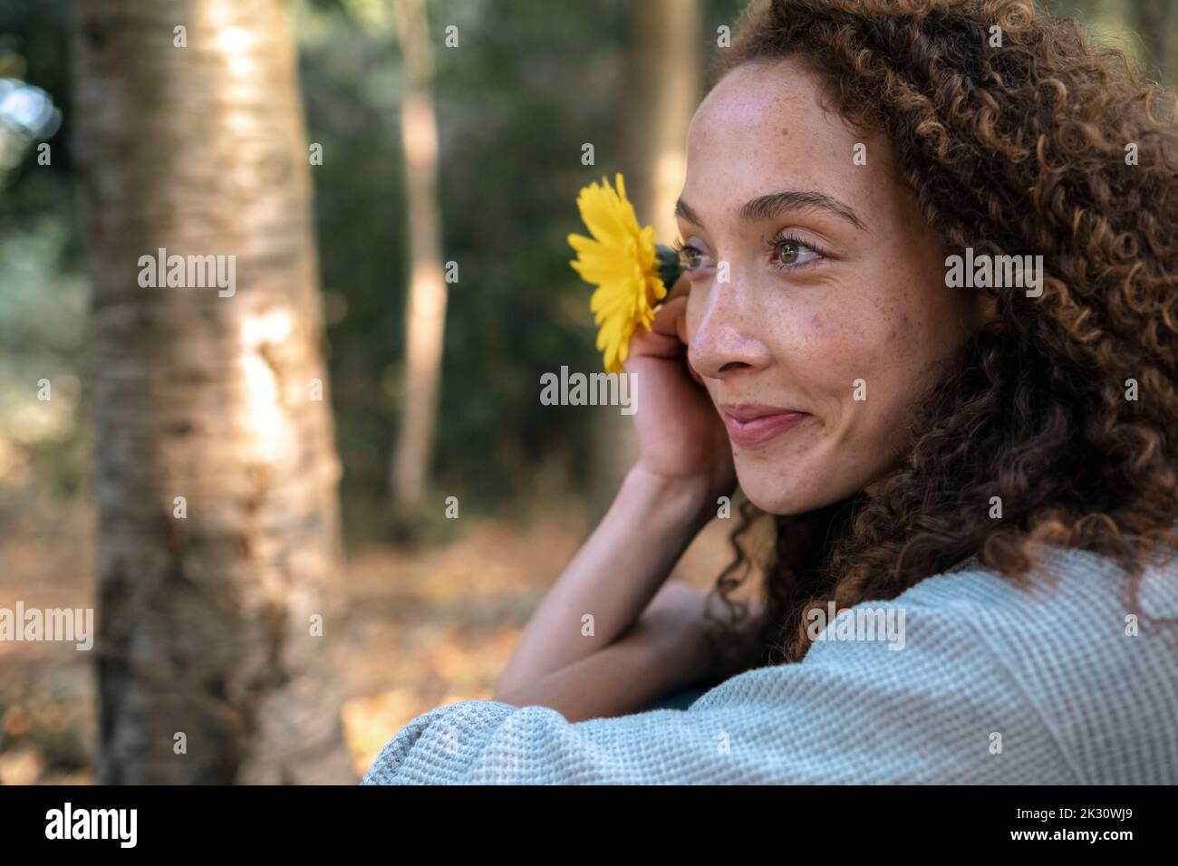 Lächelnde junge Frau mit Blume im Park Stockfoto