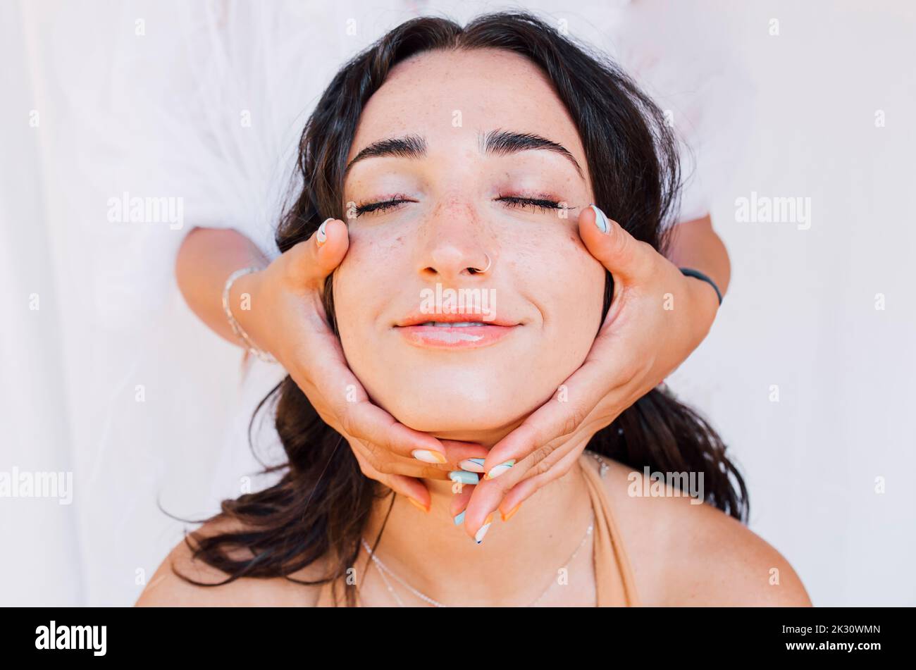 Hände berühren Gesicht der schönen jungen Frau Stockfoto