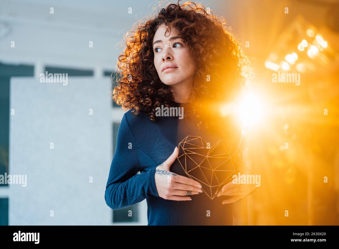 Hinterleuchtete junge Frau mit herzförmiges Modell Stockfoto