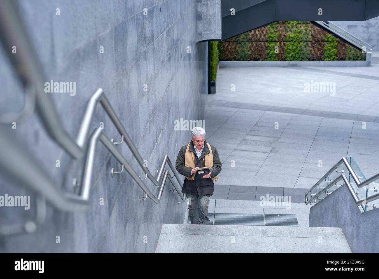 Leitender Geschäftsmann mit Tablet-PC, der sich auf der Treppe bewegt Stockfoto