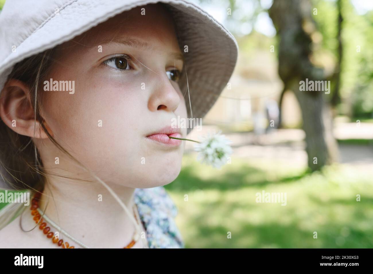 Mädchen mit Blume im Mund trägt Hut Stockfoto