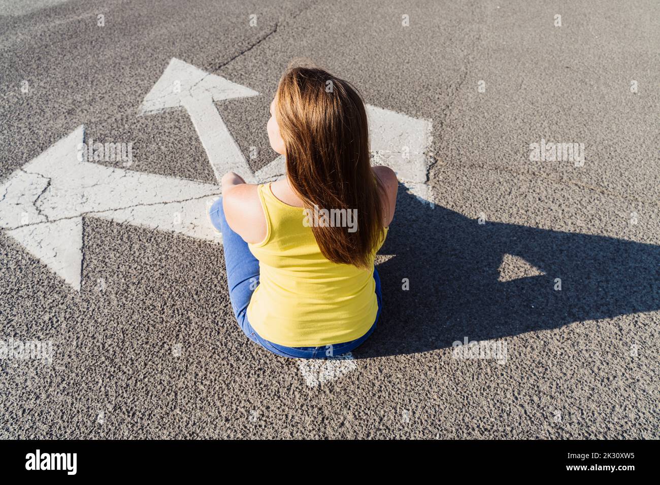 Frau sitzt auf drei-Wege-Pfeil-Zeichen Stockfoto