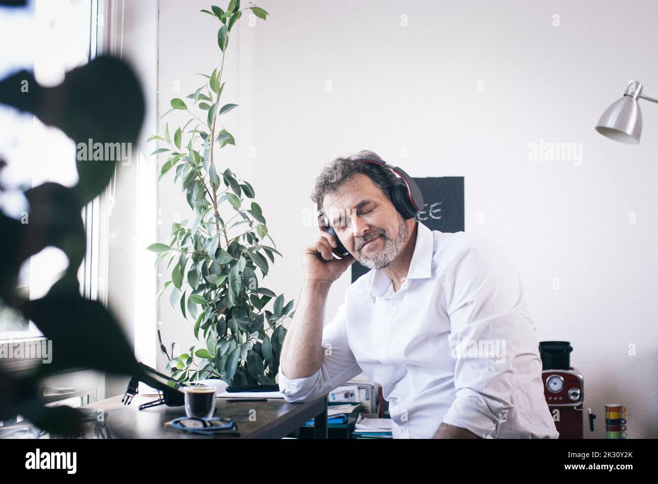 Geschäftsmann hört Musik über Kopfhörer in der Café-Ecke des Büros Stockfoto