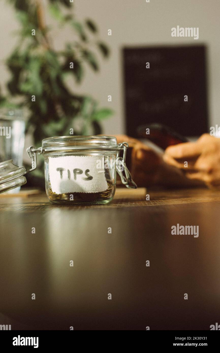 Im Café wird ein Glas mit offenem Trinkgeld auf dem Tisch aufbewahrt Stockfoto